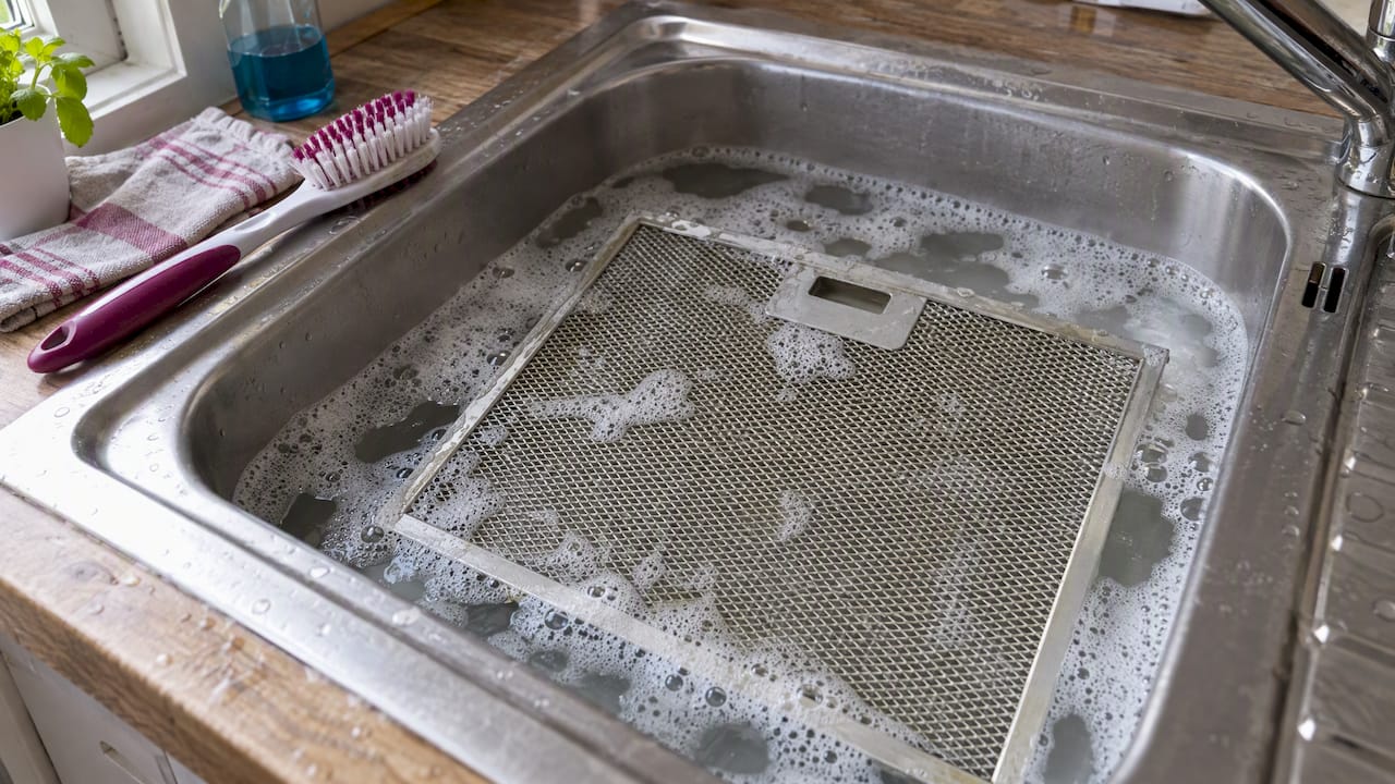 Filtre métallique de hotte plongé dans de l'eau savonneuse